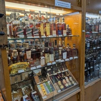 A wide shot of a vape shop shelf filled with hundreds of different e-liquid bottles in various flavors, looking overwhelming.