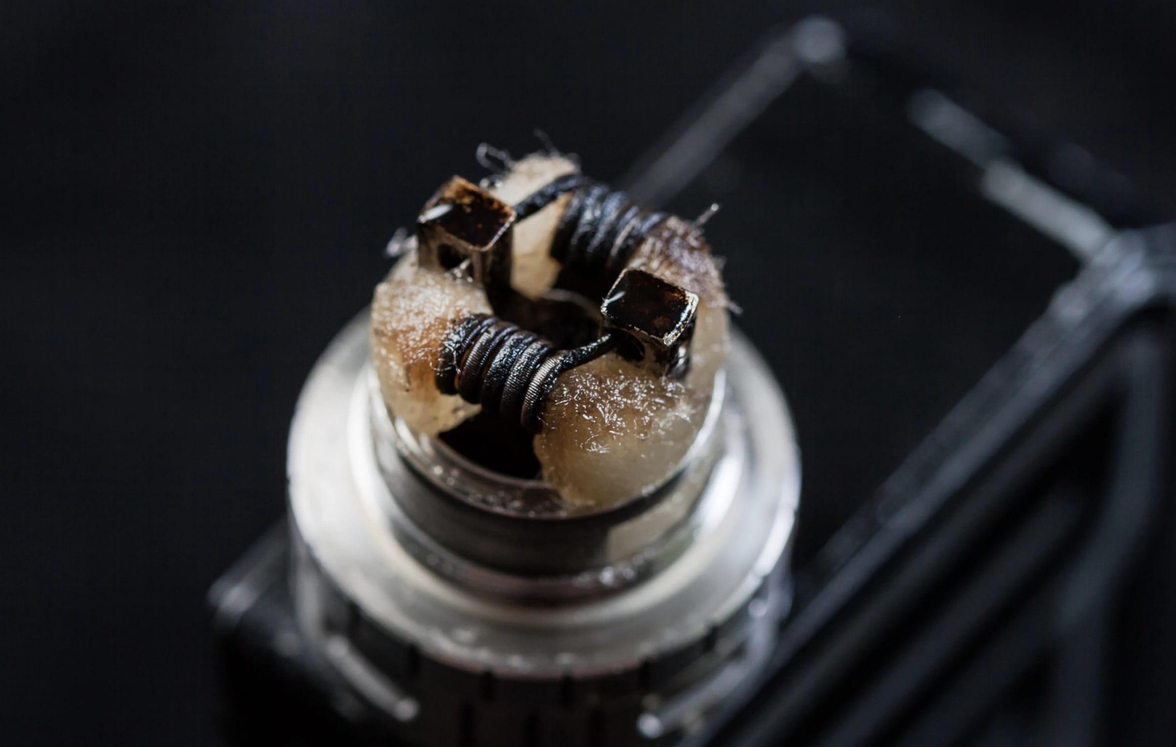 A close-up image of a vape coil covered in dark, crusty
