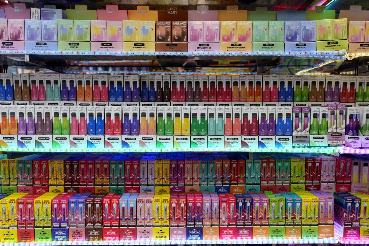 A retail shelf or display case featuring various disposable vape devices with prominent