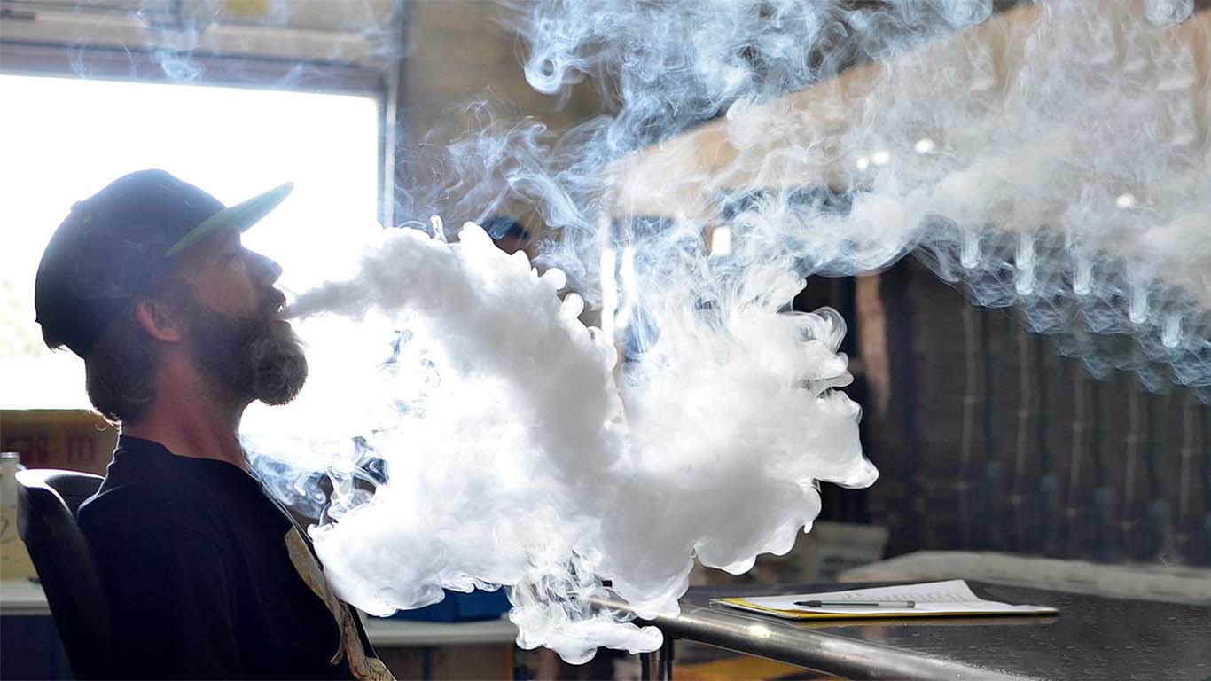 A sub-ohm vape device with a wide-open airflow control, producing a large, dense cloud of vapor, characteristic of Direct Lung (DTL) vaping.